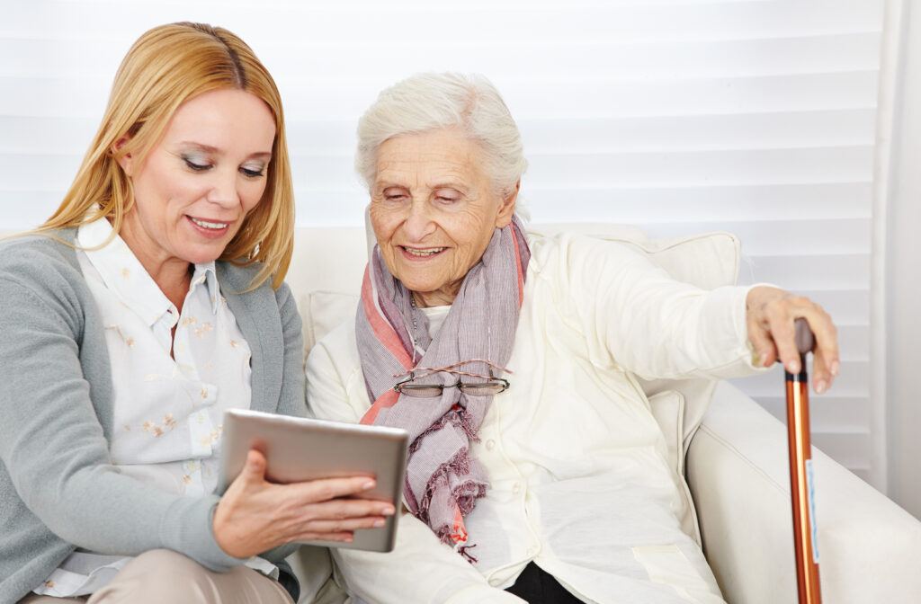 Senior women sitting with daughter deciding to know which senior services is right for her while looking at tablet