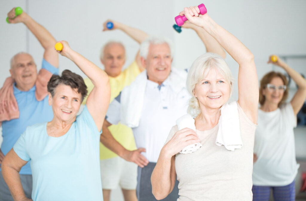 A group of seniors smiling and exercising with dumbbells' together.