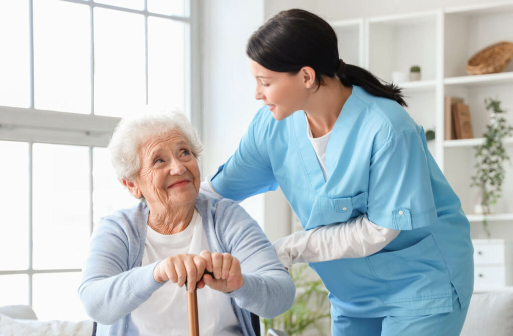 An older adult smiling in appreciation as a caregiver prepares to help them stand.